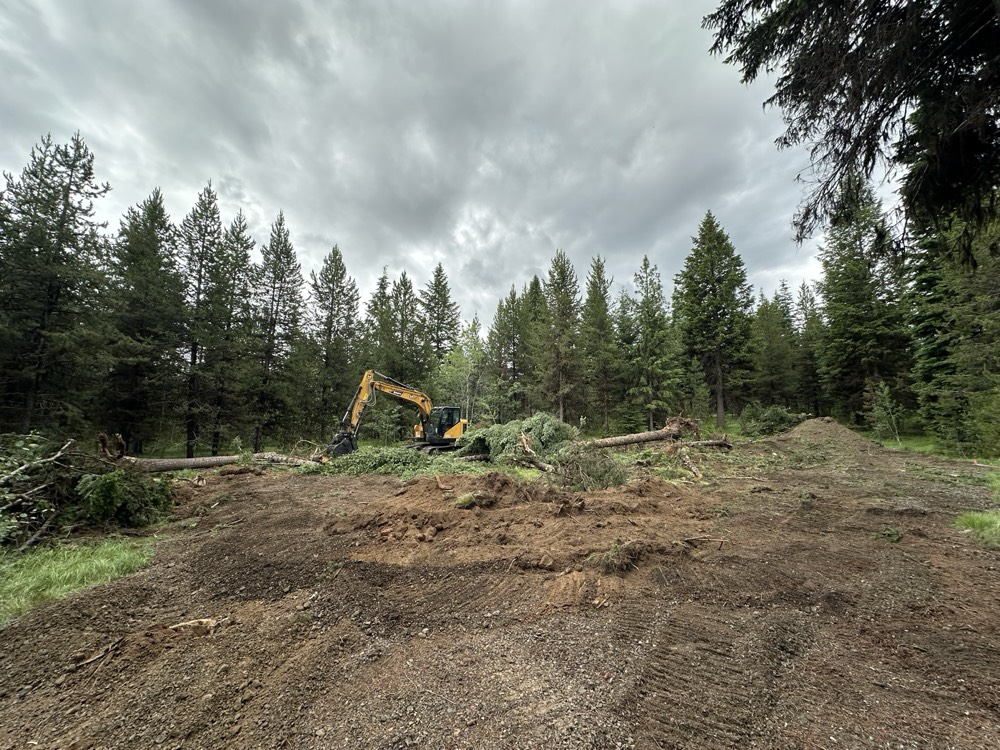 Excavator pulling trees and stumps during lot clearing